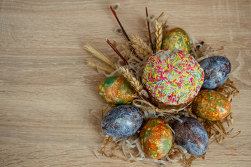 traditional Easter cake and multi-colored Easter eggs decorated with willow branches on a wooden background on the right side of the frame
