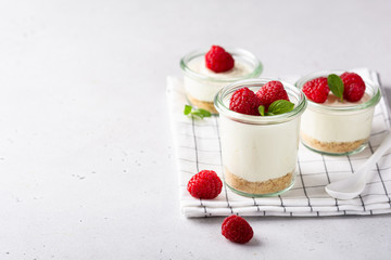 cheesecake in a glass decorated with raspberries and mint on a gray background