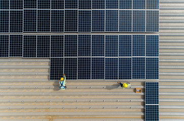 top view worker installing a solar cell on the factory roof.