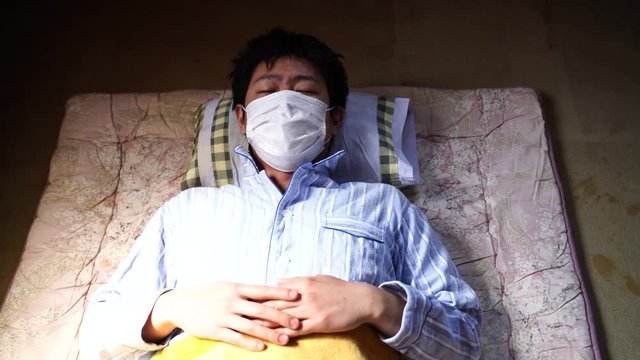 病気・寝床で咳をするマスクの男性　新型コロナウイルス感染症　イメージ
