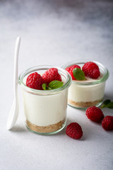 cheesecake in a glass decorated with raspberries and mint on a gray background