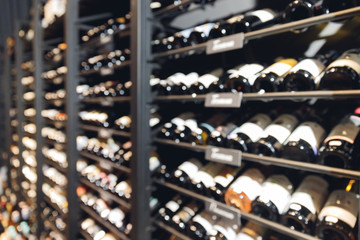 Many glass wine bottles on shelves interior in restaurant. Blurred background