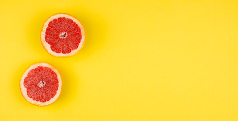 Sliced fresh grapefruit flat lay on colorful yellow background top view. Summer, holidays and vacation concept. Creative layout web and media banner template. Stock photo.