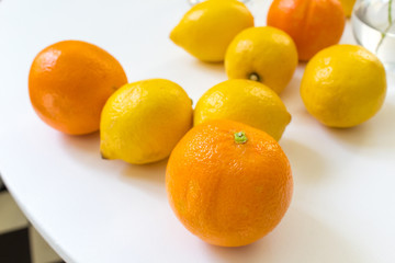 Close up oranges and lemons fruit on white home kitchen table fresh vitamin juice preparation concept 
