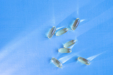 Yellow omega 3 fish oil pills on blue background close-up