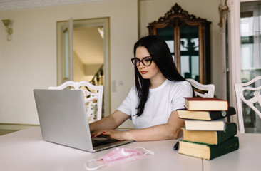 Coronavirus quarantine. Woman working on laptop at balcony. Work from home. Woman wears protection mask. Coronavirus world outbreak. Remote education and work. Stay home concept. Spring lifestyle 2020