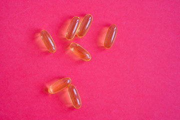 Yellow omega 3 fish oil pills on a red background close-up. Pills and dietary supplement for weight loss and a healthy lifestyle