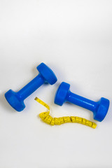 dumbbell and centimeter on a light background
