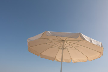 Fototapeta na wymiar white parasol in front of a sunny blue sky and hot day