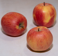 Three red apples on a white background, apples on a white table, fresh apples in the kitchen