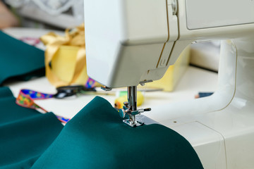 Sewing machine on the table, green cloth in the foreground. Close-up. Concept - sewing as a hobby.