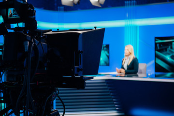 Recording at TV news studio positioned camera equipment with television presenter journalist reporting worldwide.Television announcer during live broadcast streaming.TV director/editor.Mass media
