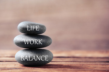 Work-life balance concept. Stacked stones on wooden table, space for text