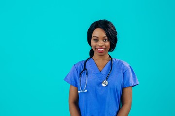 Portrait of a friendly female doctor or nurse wearing blue scrubs uniform and stethoscope and looking at camera isolated on blue background