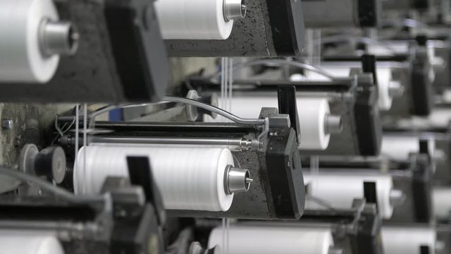 Dozens of white spools with cords making plastic bags in a modern agriculture plant