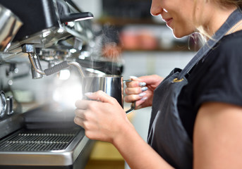 Young girl barista makes coffee on a large professional coffee machine, hands closeup. The concept of a small business and work for a student.