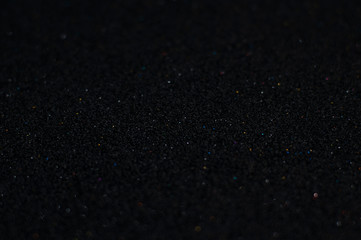 Black glitter texture abstract background. Shiny glowing colors. Concept of space, darkness, privacy, silence or mystery.