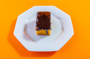Carrot cake with chocolate topping isolated on orange background. Concept photo.