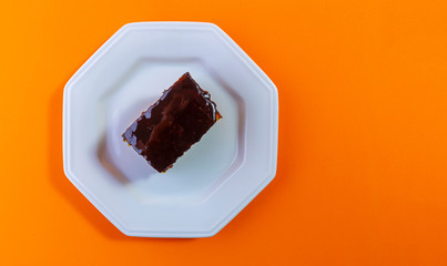Carrot cake with chocolate topping isolated on orange background. Concept photo.