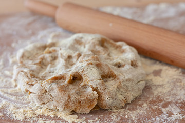 A raw piece of dough for gluten free chikpea flour chip cookies lies on a table sprinkled with flour. Gluten free chikpea flour sweet dough for homemade tea pies. Cooking sweet homemade cakes