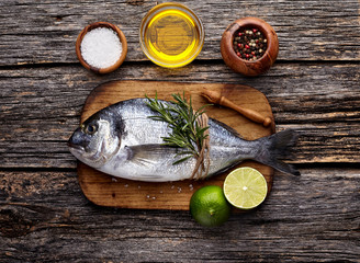 Dorado fish on the wooden  with lime, rosemary, oil and spice.  Dorado in the wooden plate. Top view.