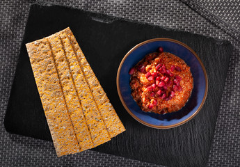 Muhammara with and crackers for dipping on slate seen from above