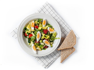 Fresh vegetable salad with mustard dressing, boiled eggs and wholewheat bread slice in a white plate (top view, white background)