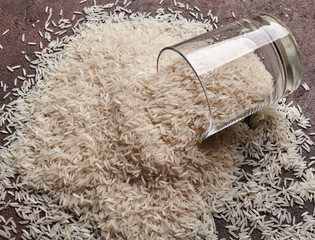 white basmati rice in a glass cup on a brown background