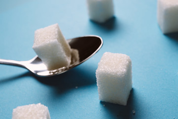 Sugar cube on a blue background shot on macro. Teaspoon sugar