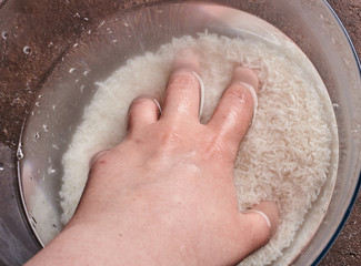 white basmati rice in water in a glass bowl on a brown background