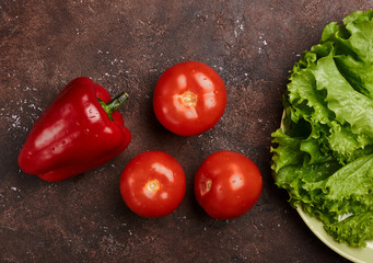 fresh veggies pepper tomatoes and lettuce on a plate on a brown background isolated
