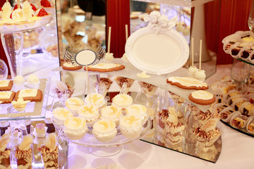 Table with sweets and goodies for the wedding party reception, decorated dessert table. Delicious sweets on candy buffet. Dessert table for a party. cakes, cupcakes.