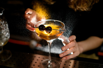 Close-up glass with ready-made cocktail accurate decorated berries and sprinkles by bartender