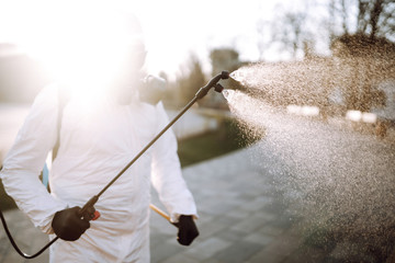 Man in virus protective suit and mask disinfects public places  with spray chemicals to prevent the spreading of the coronavirus. Infection prevention and control of epidemic. Covid-19.