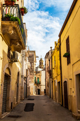 Old town street view with a church bell tower in the background in Altamura, Apulia, Italy