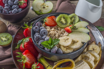 Breakfast oats. Morning oatmeal with various fruit and berries, on rustic wooden background copy space