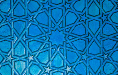 Blue wooden background. element o wooden surface with carved oriental patterns, stars, circles, triangles is tinted in light blue, turquoise color. Place for text. Copy space. Selective focus.