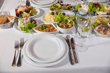 Salads and gums . Set of a dish with spoon, fork and knife on white table.Table setting on white table .