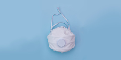 White medical mask on blue background. A protection against pollution, virus, flu and coronavirus