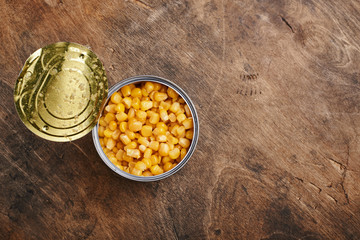 sweet corn grains in a tin open can on a wooden background