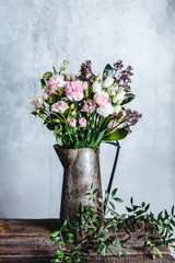 Fototapeta na wymiar bouquet of pink and white flowers in metal jug on wooden table