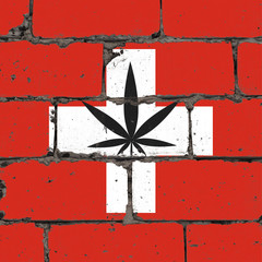 Graffiti street art spray drawing on stencil. Cannabis leaf on brick wall with flag Switzerland
