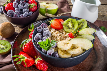 Breakfast oats. Morning oatmeal with various fruit and berries, on rustic wooden background copy space