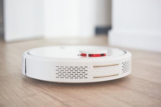 robotic vacuum cleaner on a laminated wooden floor Charging dock station Concept - Robot vacuum cleaner in the loft interior style close-up 