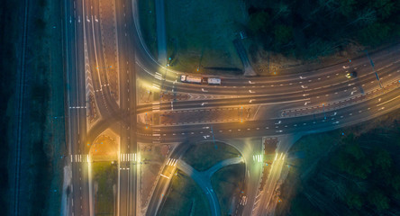 Aerial top down view on the crossroad junction with the geometric lane patterns, traffic lights and street lamps illuminating the scene