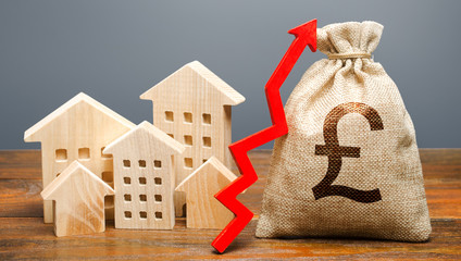 Wooden houses and a money bag with an up arrow. The concept of increasing the cost of housing. The...