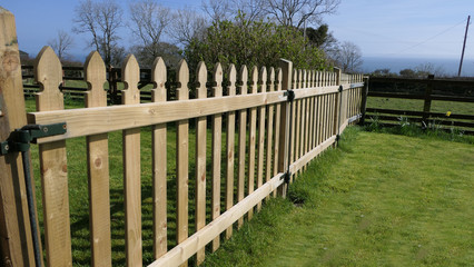 Fototapeta na wymiar Wooden fence and gate for children on garden lawn