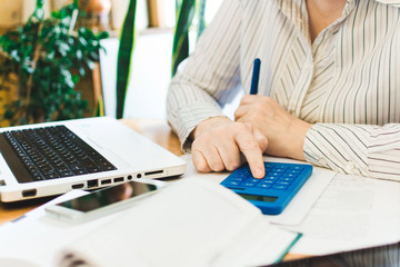 Social distancing protect coronavirus or covid-19. Closeup woman touching blue calculator. Female working in workplace at home. Accountant works remotely. Online education and distance work concept.