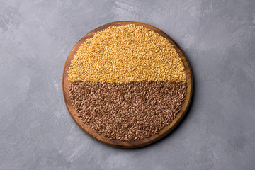 Golden and brown flax seeds on a wooden board on a gray textured background. healthy vegan superfood. horizontal