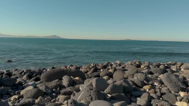 Aerial view entering the ocean from a rock beach.